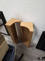 Two matching light wood curved-front vertical shelves standing side by side