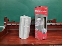 Boxed Imperial dryer vent hose and sealed vent hose side by side on wood surface