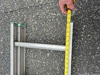 Top section of ladder side rail and rung with tape measure showing dimensions