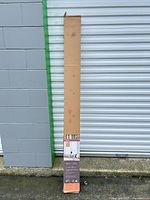 Full view of long boxed Allen+Roth faux wood blind leaning against storage unit