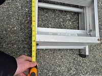 Close view of ladder end with tape measure showing rung spacing and material