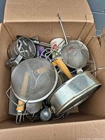 box containing assorted stainless strainers, utensils
