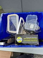 Overall lot in blue bin with grater, colander, containers, cutlery box visible