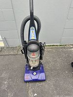 Front view of Bissell PowerForce upright vacuum showing bagless dust cup, hose, cord, and base