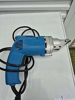 Full view of blue corded metal shear nibbler lying on table