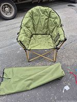 Folding olive moon chair unfolded with carry bag on ground