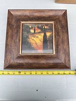 Front view of framed landscape print with measuring tape showing ~12 in width