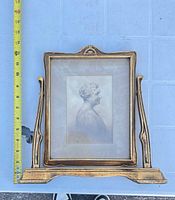 Front view showing gold gilded frame with portrait photo, integrated stand, and tape measure indicating height