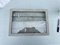 Top view of closed gray velvet jewelry display with earrings inside