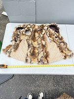Full view of faux fur vest laid flat showing front, cable-knit panels and tape measure for scale