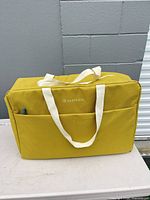 Front view of mustard yellow KeepCool soft cooler bag showing handles and pocket