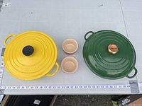 Top view of both cookware lids and two ramekins with scale for size reference