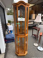 Full view of oak hexagonal corner curio cabinet showing glass panels, doors, and shelves