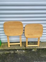 Two folding TV tray tables standing folded against wall