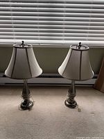 pair of matching table lamps standing on floor with shades attached