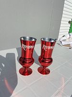 Front view of both red Riviera metal glasses standing on table