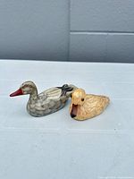 Both carved wooden duck figurines side by side