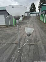 Full view of silver brushed nickel torchiere floor lamp with attached reading light and frosted glass shades