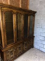 Full view of dark brown solid wood china cabinet with metal grille doors and carved base