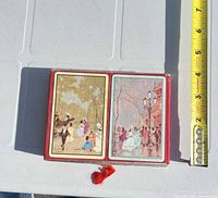 Closed red double box showing two deck backs with painted scenes