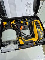 Open carry case showing sprayer gun with cup, power cord, spare parts bag and paperwork