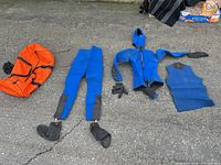 Full set laid out: orange bag, pants with booties, hooded jacket, gloves, vest