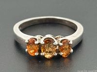 Front view showing three orange gemstones set in sterling silver band
