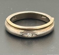 Close view of ring showing clear stone, gold-tone overlay, hallmarks