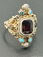 Front angled view showing garnet, turquoise, pearls and ornate silver work