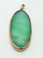 front view of oval green stone pendant in gold-tone bezel