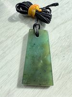 Front view of greenstone jade pendant on cord
