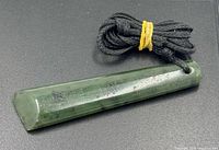 Greenstone pendant front view showing drilled hole and cord