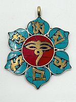 Front view of lotus pendant showing turquoise inlay, red center, Tibetan characters