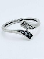 Front view of sterling silver bypass ring showing white and black diamond pavé tips