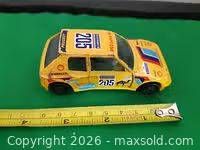Left side view of yellow Peugeot 205 diecast with tape measure showing length