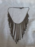Full view of bib necklace showing cascading chain fringe and clasp