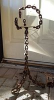 Full view of cast iron chain-link stand showing height and three-leg base