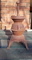 Full front view of cast iron miniature stove showing ribbed barrel body, door and legs