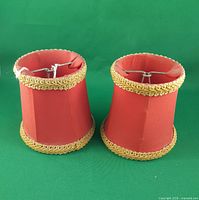 two red clip-on chandelier shades upright showing exterior fabric and gold trim