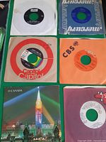 Front view of all six 45 RPM records in sleeves laid out on green surface