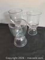 Three clear heavy glass rummer glasses on dark surface