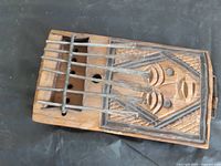 Full view of kalimba showing body, tines, sound hole, and carved face