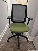 Front view showing full chair with green seat, mesh back, armrests, five-wheel base