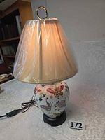 Full view of lamp showing porcelain base, butterfly pattern, shade, cord and finial