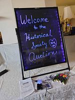 LED message board on stand lit purple with accessories in front