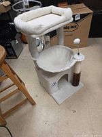 Full view of cat tree showing top perch, hammock, cubby, scratching post, toys and groomer