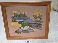 Front view of framed crewel embroidery floral rock garden artwork