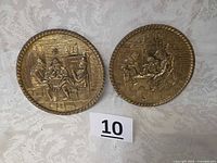 Front view of two circular brass plates showing embossed designs