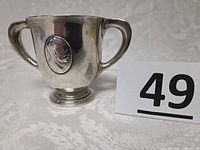 Front view showing double handles, footed base, profile medallion