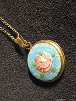 front view of round guilloche enamel locket pendant with chain, showing rose motif